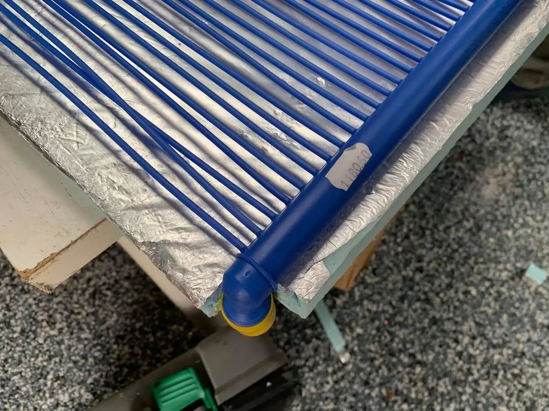 Close-up of blue polypropylene capillary tube mat being positioned on an insulation panel